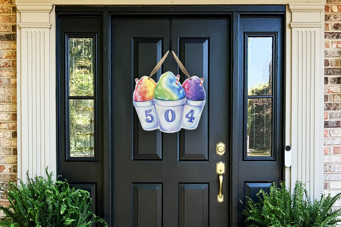 Decorative, colorful Snoball door hanger with numbers 504 on them on a black door.
