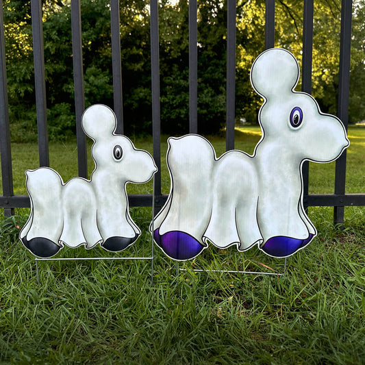 Two Ghost Bead Dog-shaped signs in purple and black colors on grass in front of a fence.