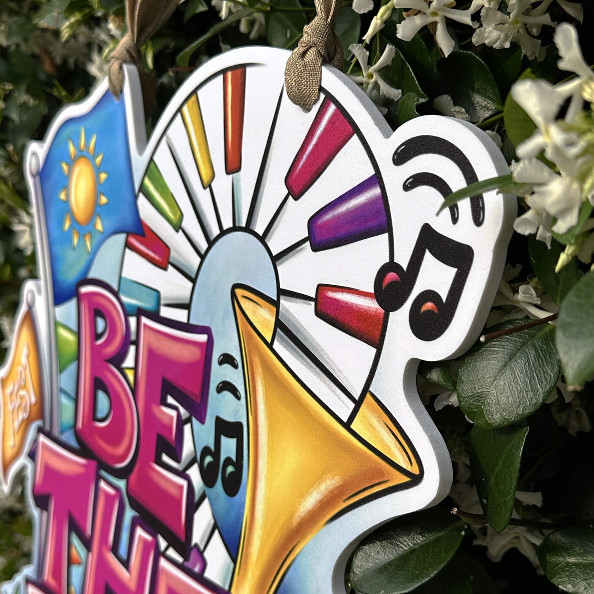 Decorative sign with colorful design and text 'BE THE VIBE' on a natural background