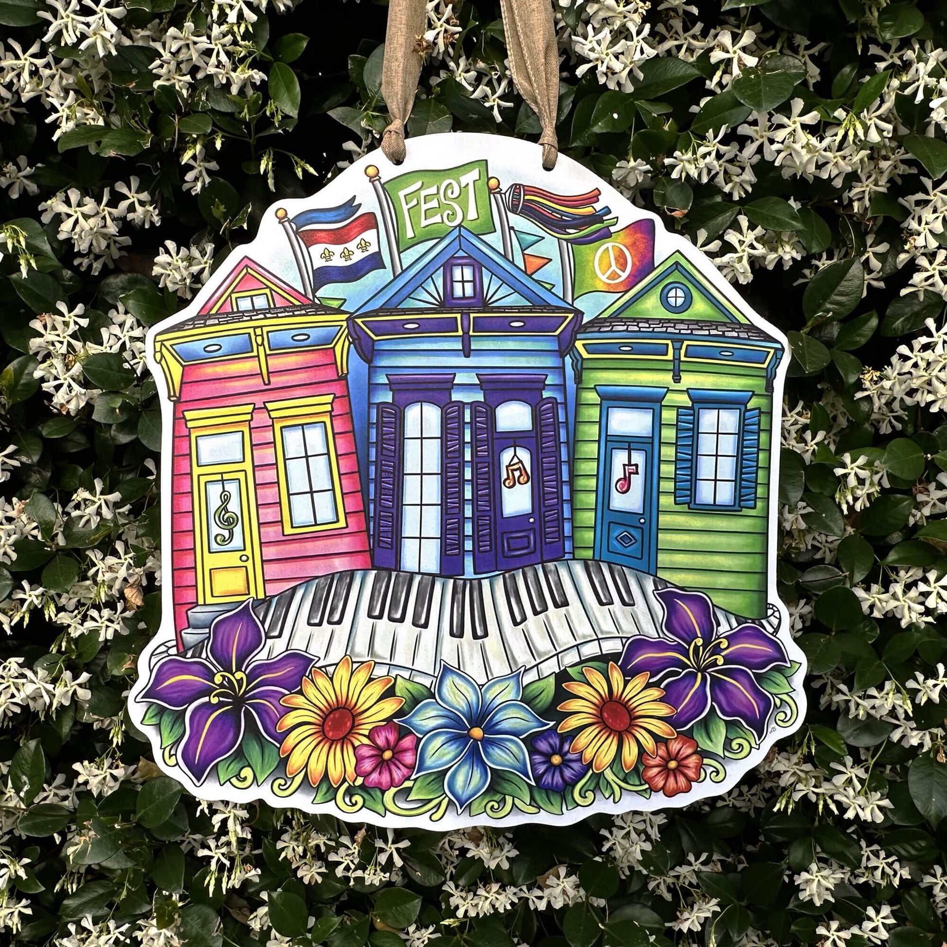 Decorative door hanger with colorful shotgun houses and flowers on a floral background with a keyboard sidewalk and festival flags flying behind the colorful houses