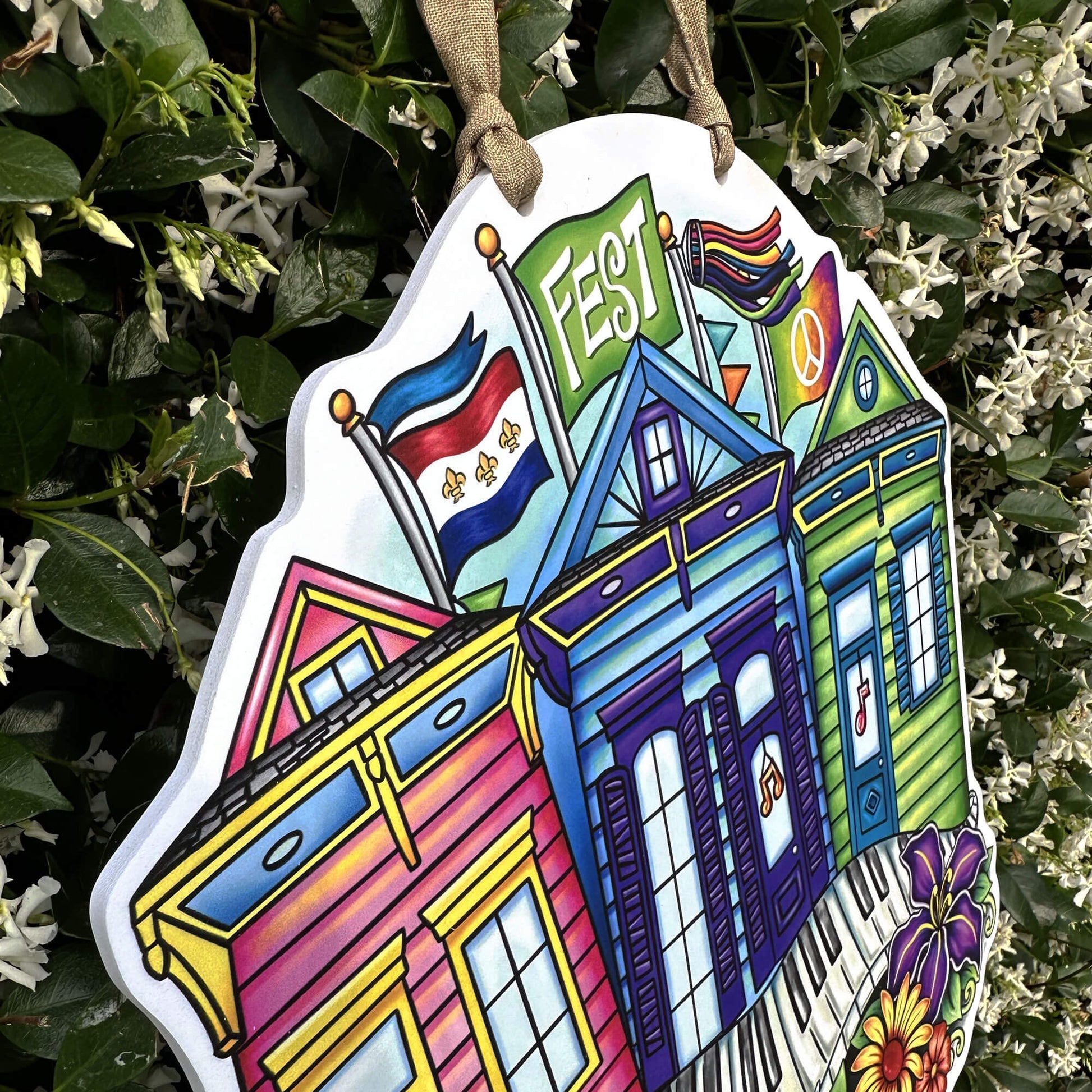Colorful decorative sign with shotgun houses and flags on a green leafy background