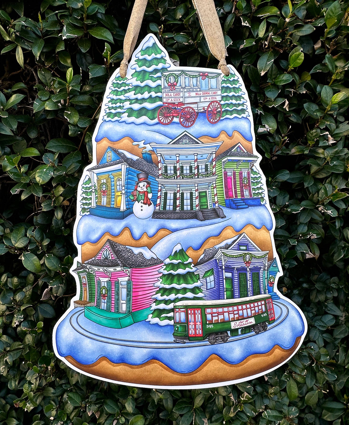 Decorative Christmas door decor with a snowy village scene of colorful New Orleans shotgun homes on a green leafy background